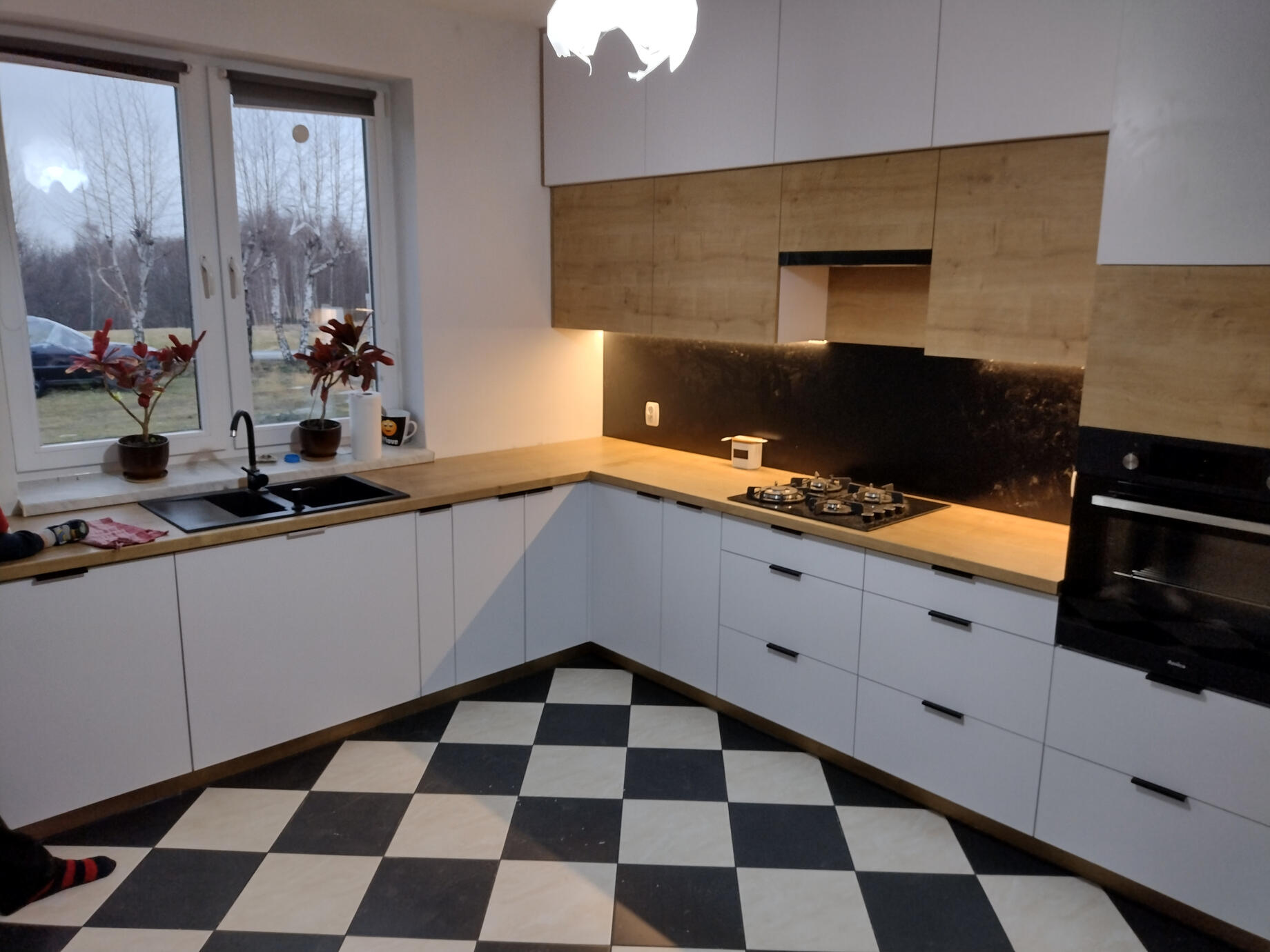 Białe fronty szafek sięgające sufitu optymalizują przestrzeń, tworząc wrażenie większej wysokości i czystości linii.